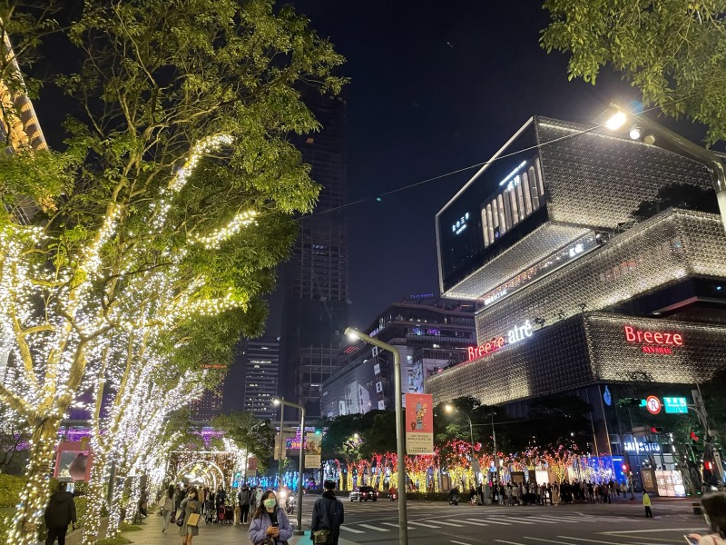 A vibrant street scene in Taipei at night, illuminated by the festive lights of the Lantern Festival, with crowds of people celebrating.