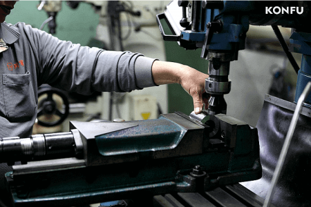 Operator overseeing a CNC machine during the production of a precision header die.