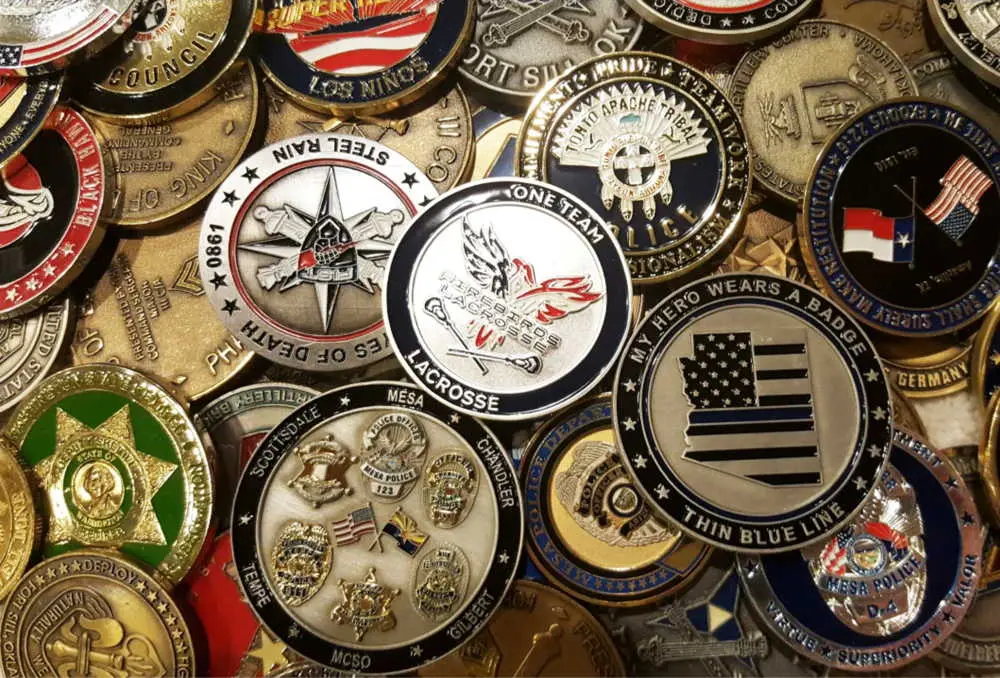 A diverse assortment of challenge coins for military, law enforcement, or organizational purposes, featuring various designs like flags and logos.