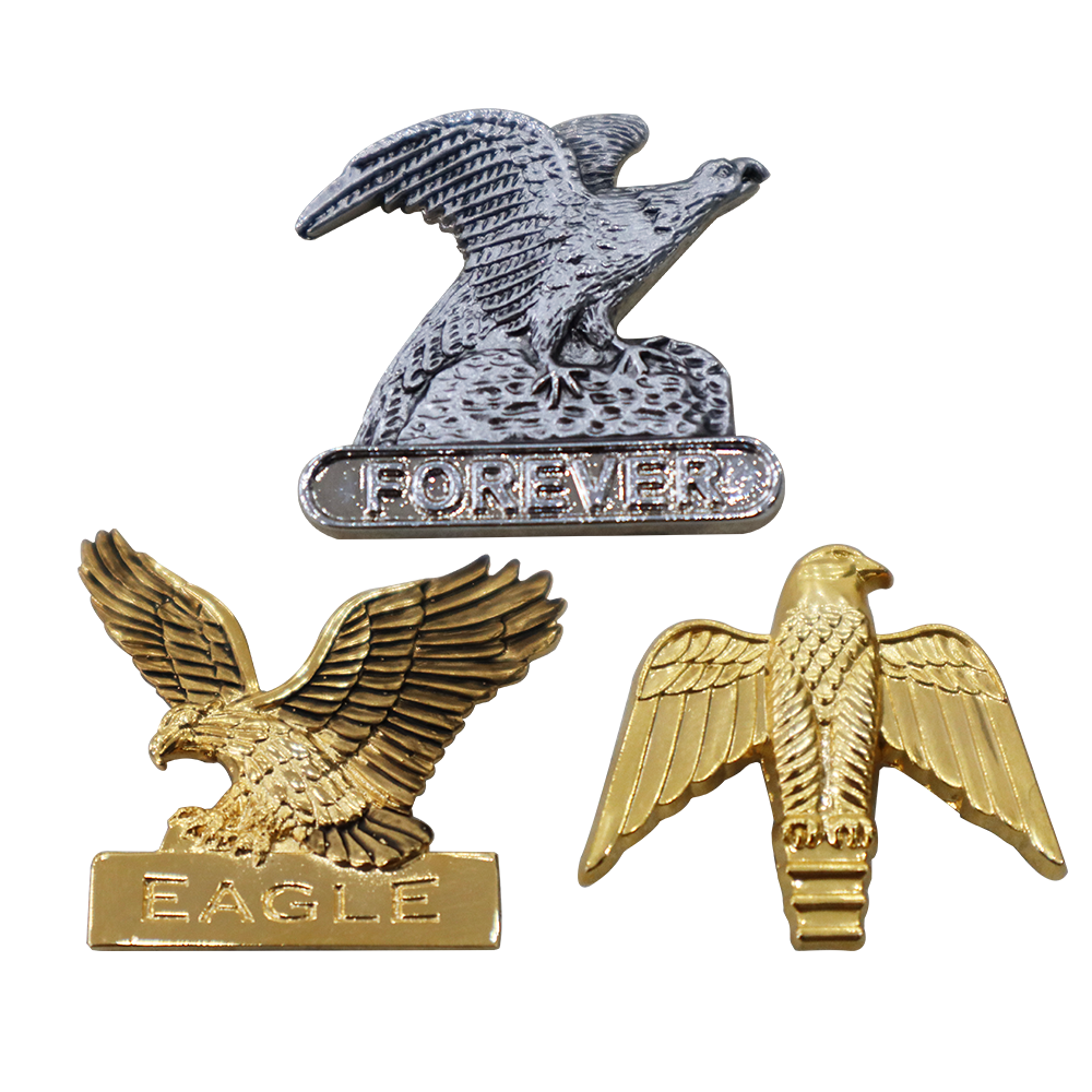 Three eagle-themed metal pins, two in gold and one in silver, with distinct engravings, showcasing the no-coloring craft.