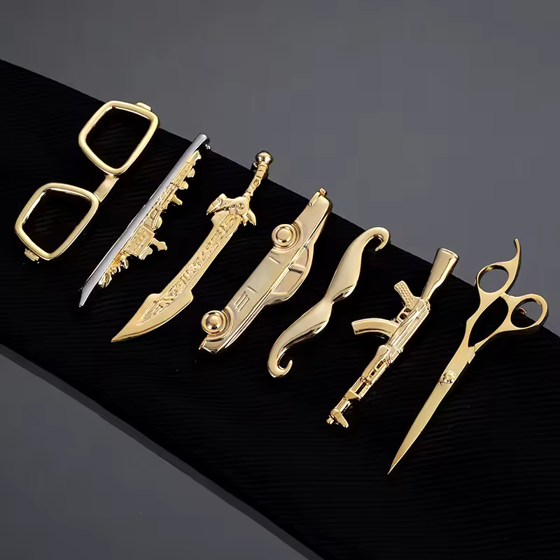 A collection of sleek, gold-plated metal tie clips and accessories on a dark background.