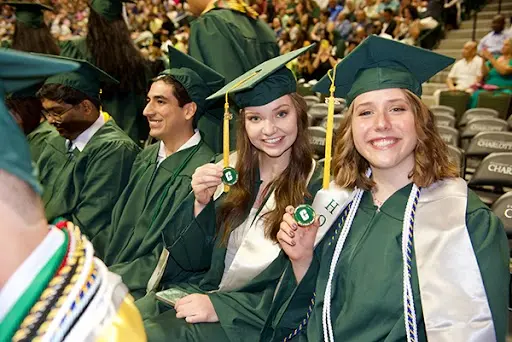 Graduation ceremony with students in green gowns and caps
