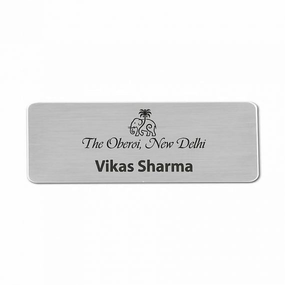 Luxury hotel staff name badge with minimalist logo engraving on silver aluminum; high-end finish for premium hospitality brands.