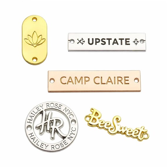 Custom Metal Label Tags - Custom metal logo plates in polished gold, silver, and rose gold finishes; high-quality embossed branding labels for luxury handbags and accessories.