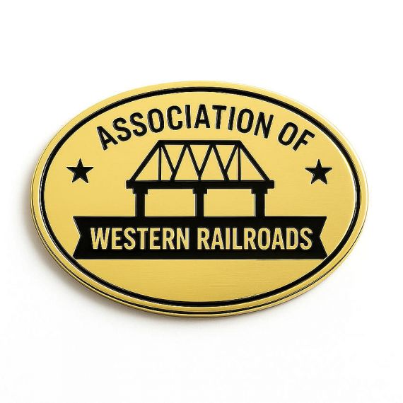 Oval gold brushed metal nameplate with black embossed lettering reading Association of Western Railroads, featuring a railway bridge silhouette and star accents.