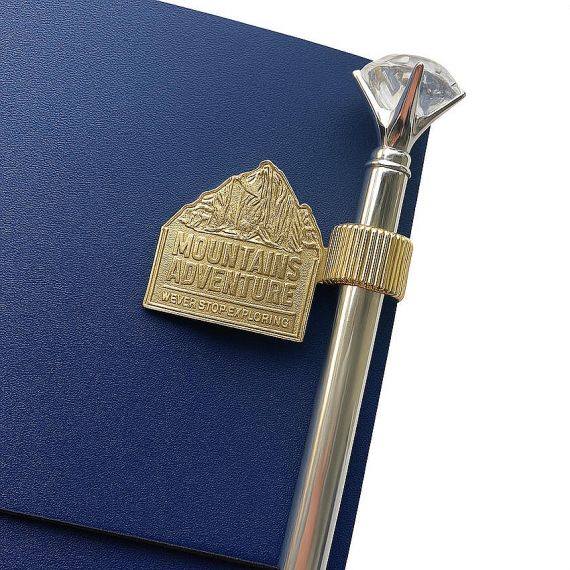 Bespoke "Mountains Adventure" gold embossed metal pen holder, personalized heavy-duty notebook clip for outdoor enthusiasts.