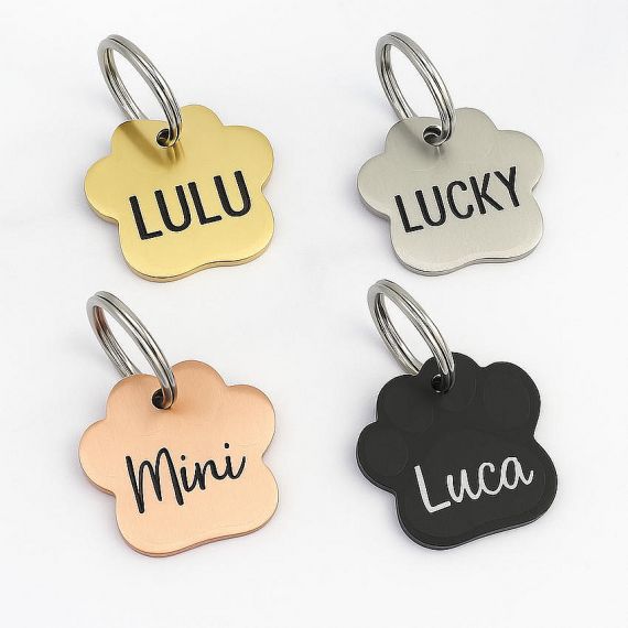 Laser engraved dog names are clearly displayed on paw print shaped metal pet ID tags in matching gold, silver, and rose gold finishes.
