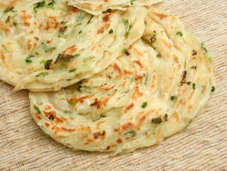 Chopped Scallions are evenly distributed on the Lachha Paratha