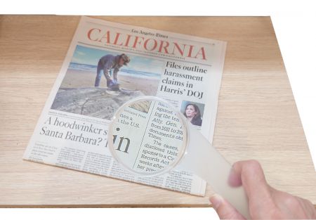 新聞を読むプラスチック製の手持ち拡大鏡