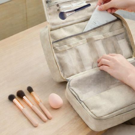 Open rPET hanging makeup organizer with mesh compartments storing cosmetics, makeup brushes, and beauty tools.