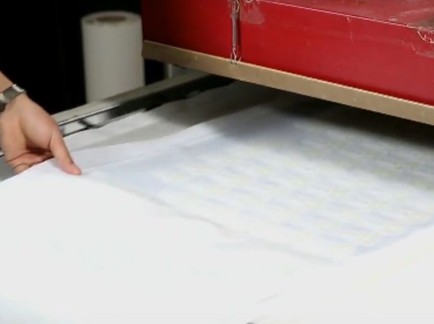 A aplicação de adesivo na parte de trás do bordado através de prensa térmica