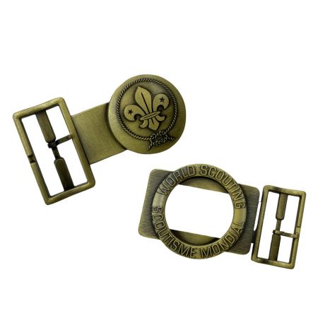 หัวเข็มขัดเข็มขัดลูกเสือแบบกำหนดเอง 2 ชิ้นที่มีการตกแต่งด้วยทองเหลืองโบราณ พร้อมสัญลักษณ์ฟลูร์-เดอ-ลิสและวงแหวนลูกเสือโลกที่แกะสลัก แสดงในส่วนประกอบที่แยกออก