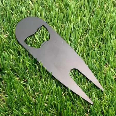 เครื่องมือซ่อมหลุมกรีนที่มีสีดำอิเล็กโตรโฟเรซิสบนพื้นหญ้า