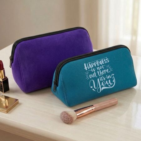 Custom neoprene makeup bags in teal and purple with printed logo displayed on a vanity table with cosmetics