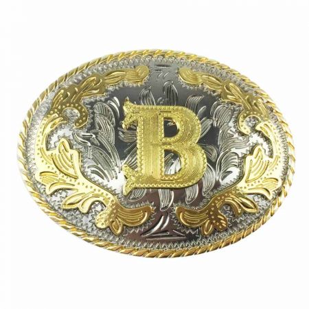 Kaksivärinen vyönsolki, jossa kultainen B hopeataustalla