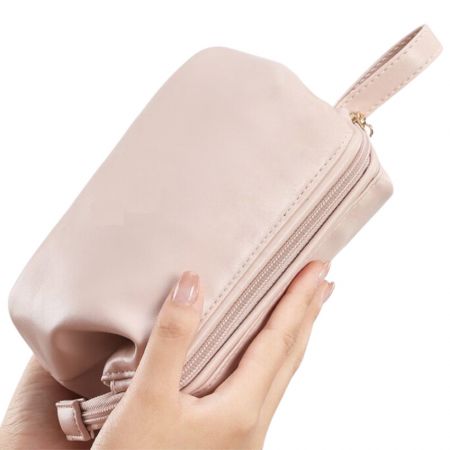 A pink faux leather amenity bag held by two hands