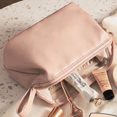 Leather cosmetic bag turned sideway with cosmetics falling out of bag