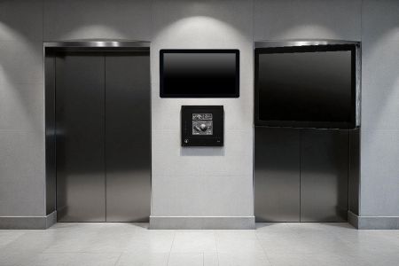 Panel PC alkalmazások áruházak információs pultjaiban és liftcsarnokokban - Egy falra szerelt panel PC, amely a liftek közelében található, digitális információt és interaktív szolgáltatásokat nyújt a vásárlók számára.