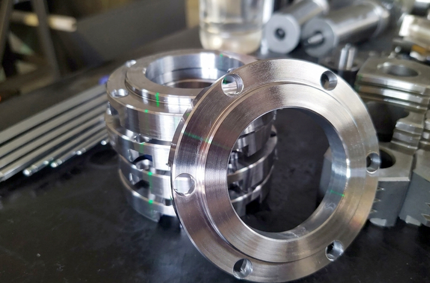 A stack of steel or metal flange plates and ring components precisely machined using the 2ST36 CNC turn-mill machine.