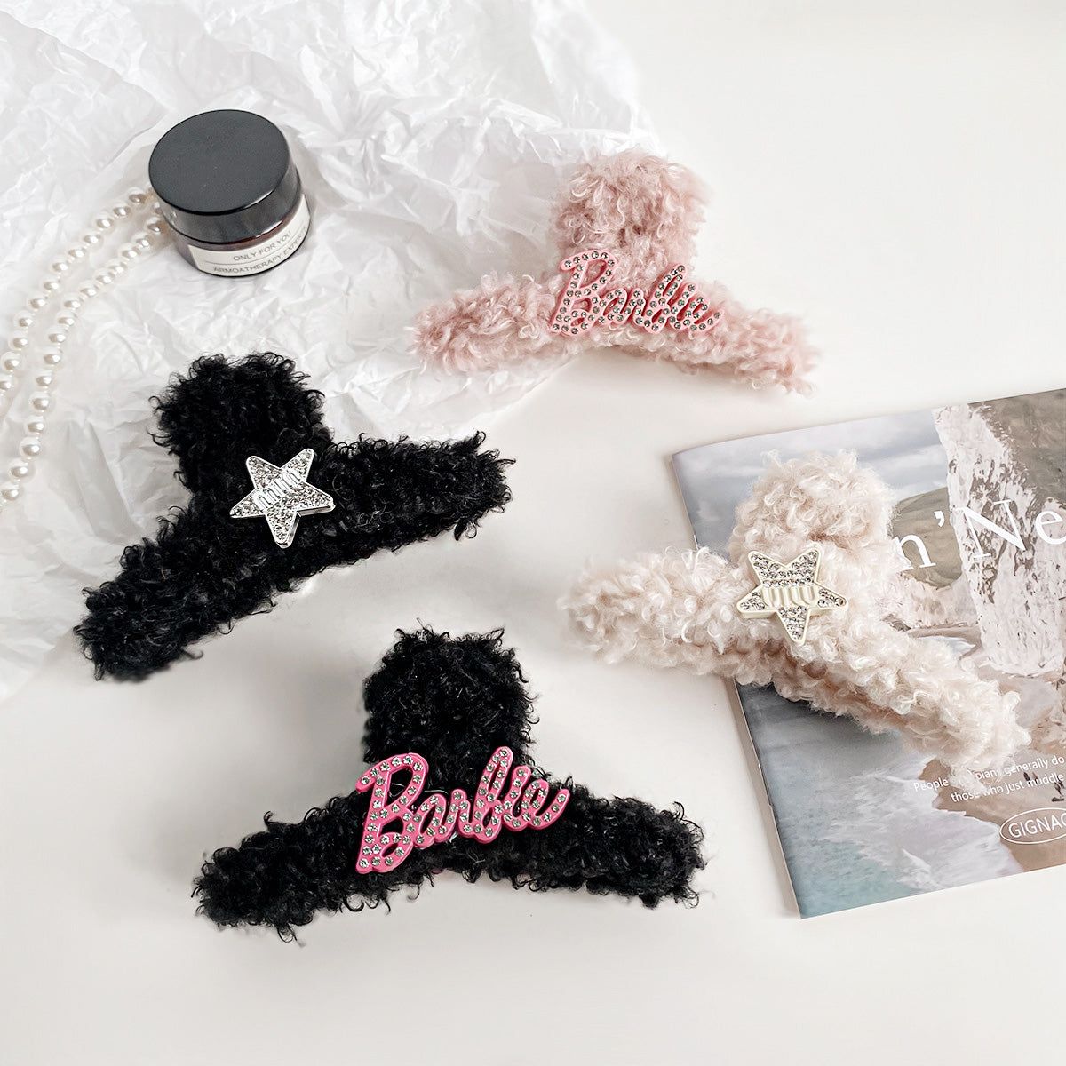 Uma coleção de clipes de cabelo de pelúcia fofos para atacado em vários estilos, incluindo designs com tema da Barbie, em forma de estrela e decorados com strass, exibidos em um fundo rosa.
