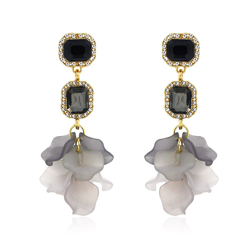 Un par de pendientes de pétalos de flores colgantes con un acabado chapado en oro, que exhibe un diseño floral con piedras de cristal negras y grises sobre un fondo blanco.