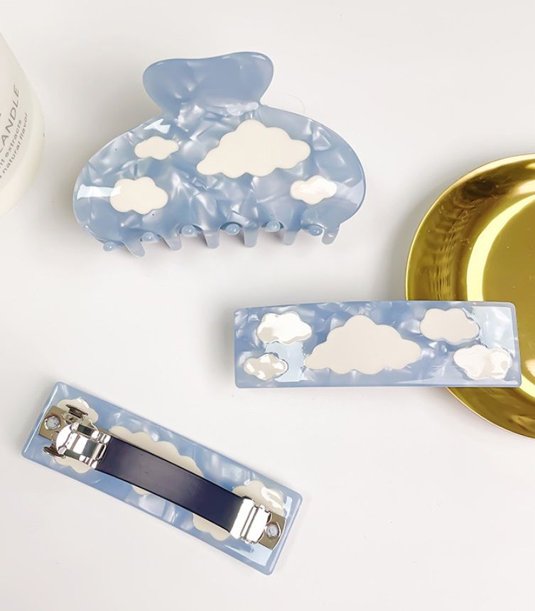 A pair of stylish wholesale blue acetate hair clips with a charming white cloud pattern, offered by JR Fashion Accessories.