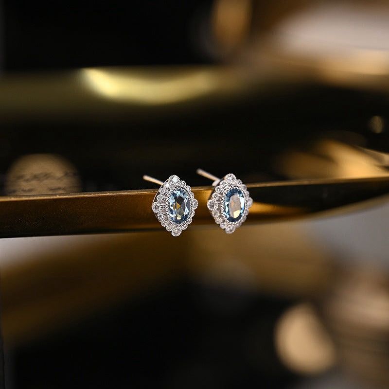 Un paio di orecchini a perno a rombo in stile vintage in argento sterling 925 placcato oro, con una zirconia cubica acquamarina centrale.