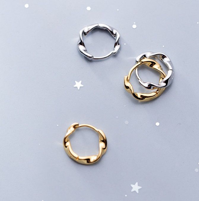 Un primer plano de los pendientes de aro de onda de plata esterlina 925 en acabados plateado y dorado, mostrando su diseño único y elegante.