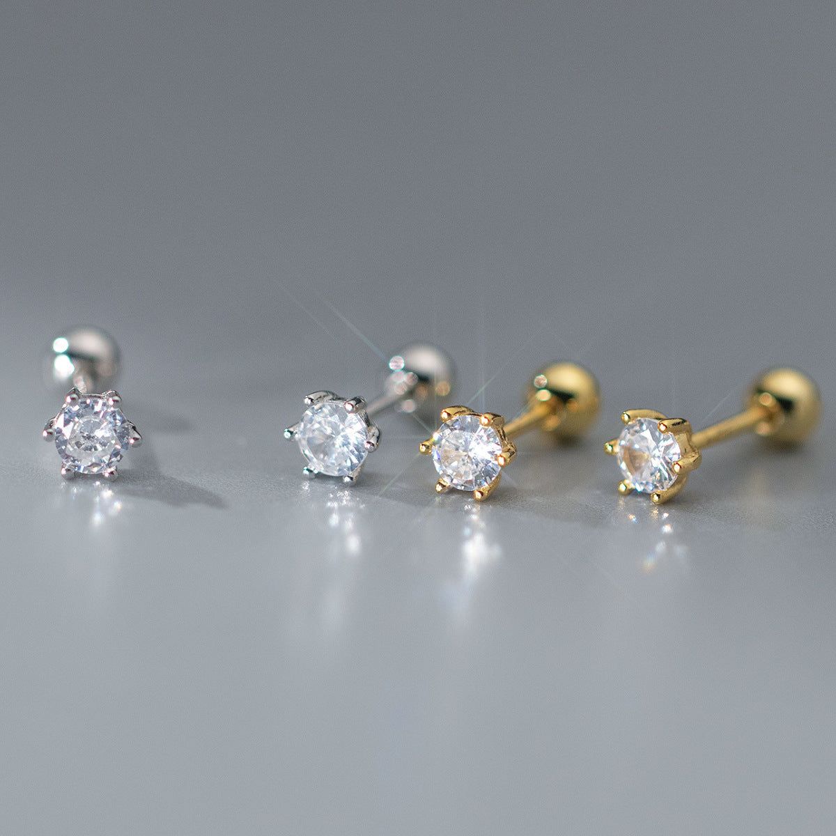 A collection of 925 sterling silver six-prong stud earrings with brilliant cubic zirconia, displayed in both silver and gold finishes.