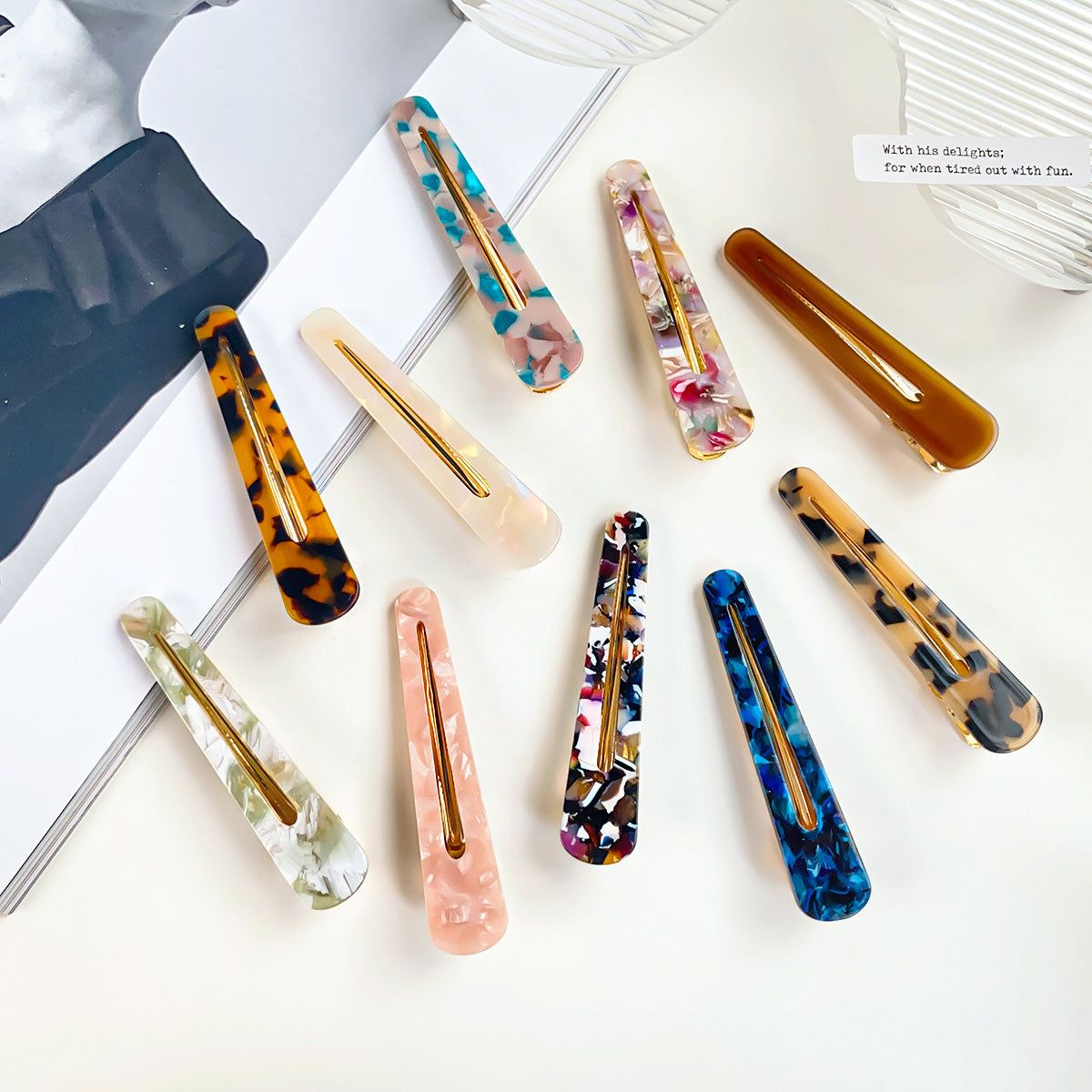 Een levendige collectie van dames haarclips met eendenbek in verschillende gemarmerde acetaatpatronen en kleuren, weergegeven op een neutrale achtergrond.