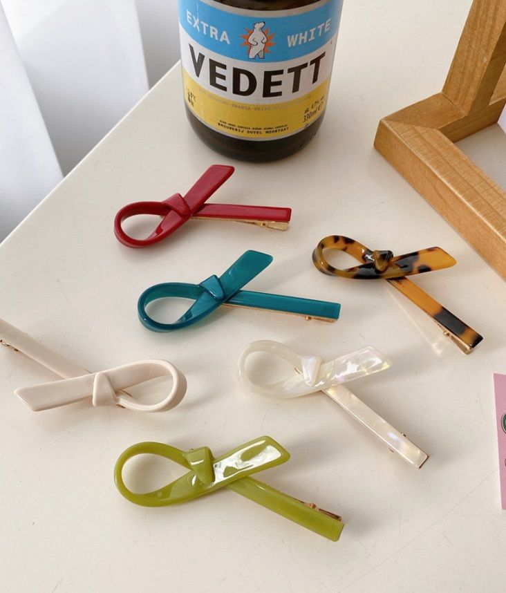 Una colección de coloridos clips de cabello de cinta al por mayor de JR Fashion Accessories, exhibidos en una mesa.