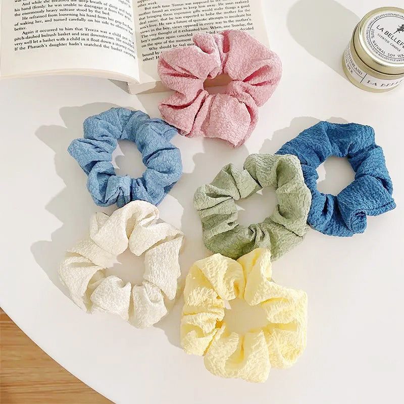 Uma coleção vibrante de seis scrunchies de cabelo em cores de doce para meninas, exibidos de forma organizada em um fundo branco.