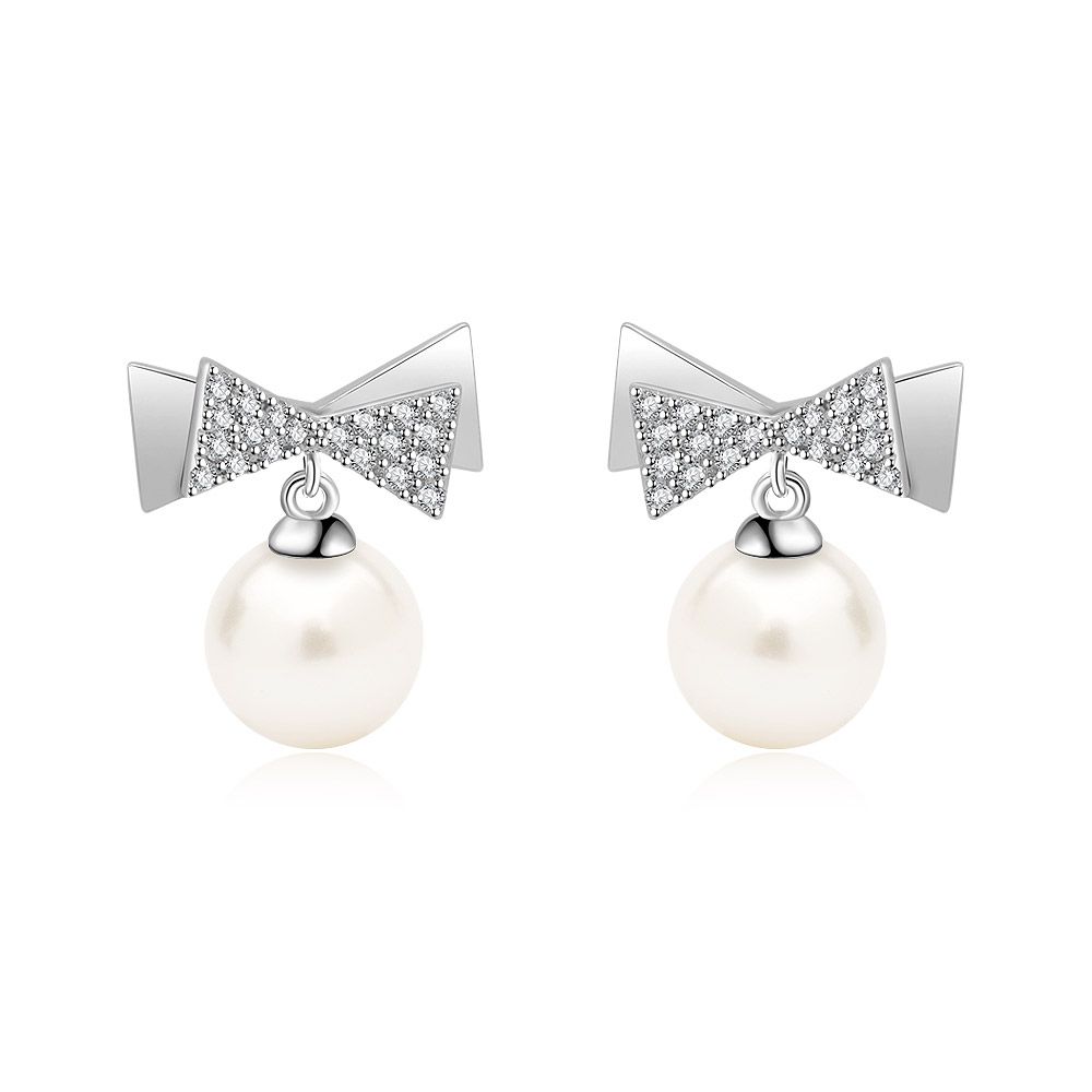 Un primer plano de los pendientes de perla en forma de lazo de 7 mm, mostrando el intrincado diseño de lazo engastado con diamantes y la perla de agua dulce blanca y lustrosa.
