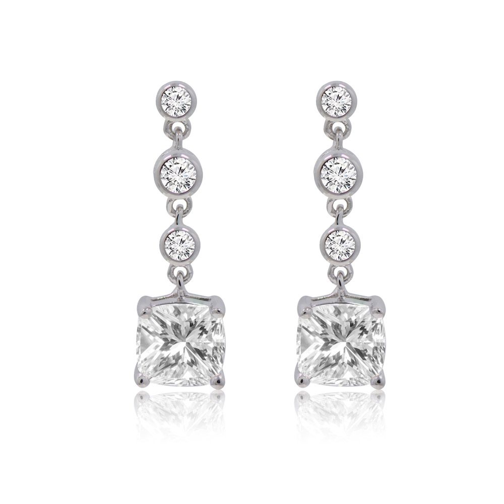 Une paire de boucles d'oreilles pendantes en forme de coussin avec une grande pierre en zircon cubique taillée en carré suspendue en dessous de trois petites pierres rondes, le tout monté en laiton plaqué rhodium.