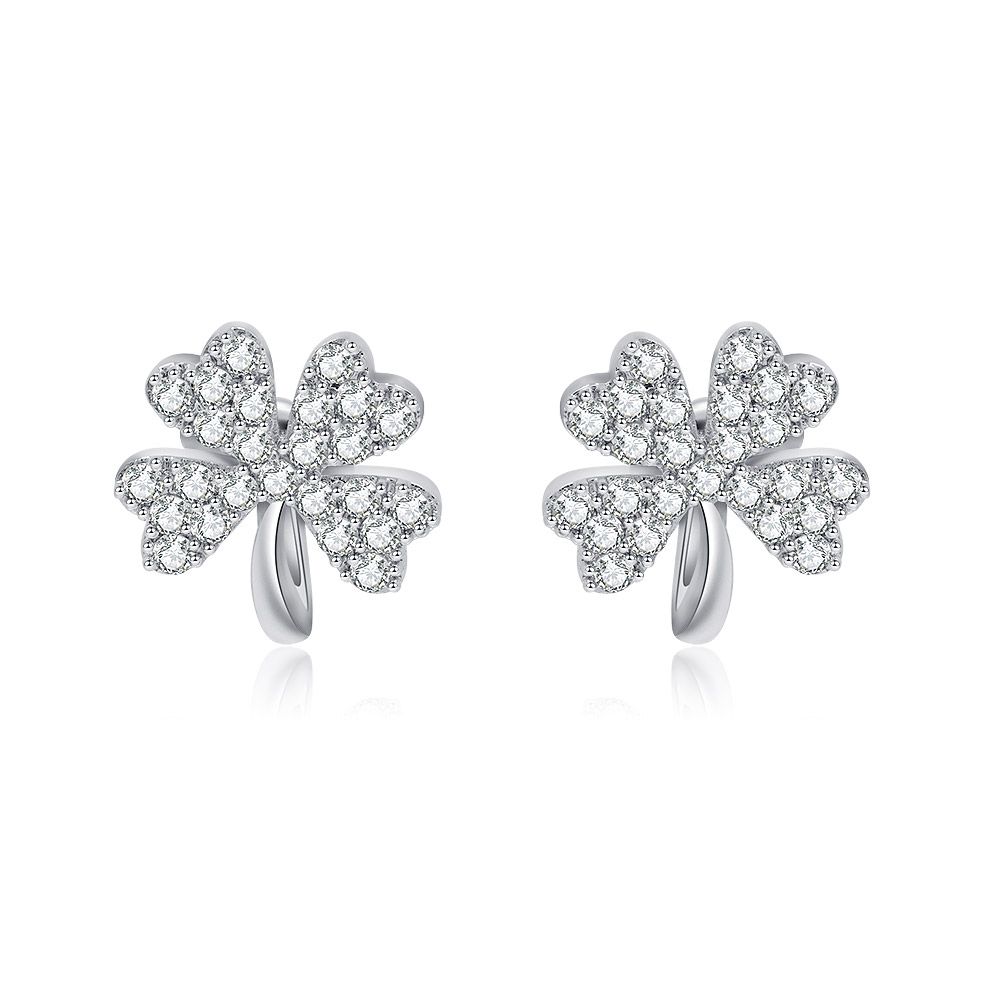 Un par de pendientes de clip de plata con forma de trébol de hoja de la suerte, adornados con piedras de circonio cúbico brillantes, sobre un fondo blanco.