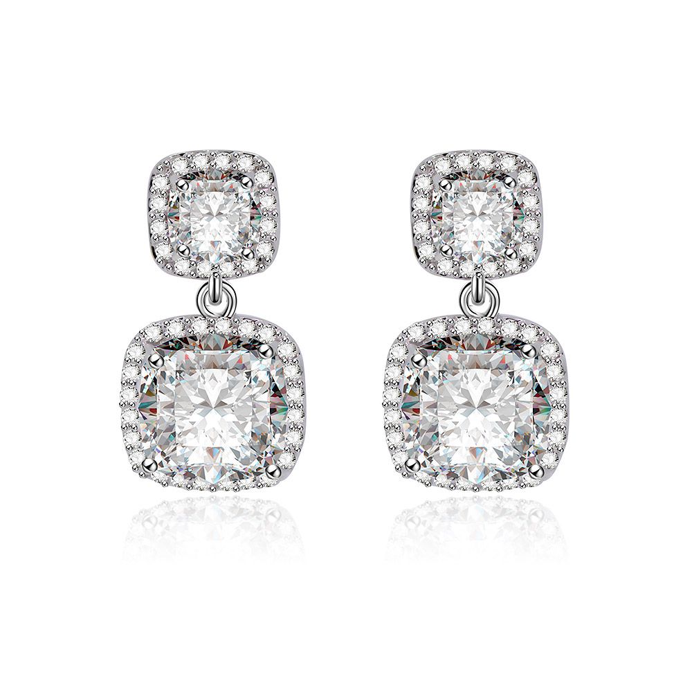 Une paire de boucles d'oreilles pendantes de mariage en taille coussin avec un design en deux parties, présentant des pierres en zircon cubique de forme carrée dans des montures élégantes en halo sur un fond blanc.