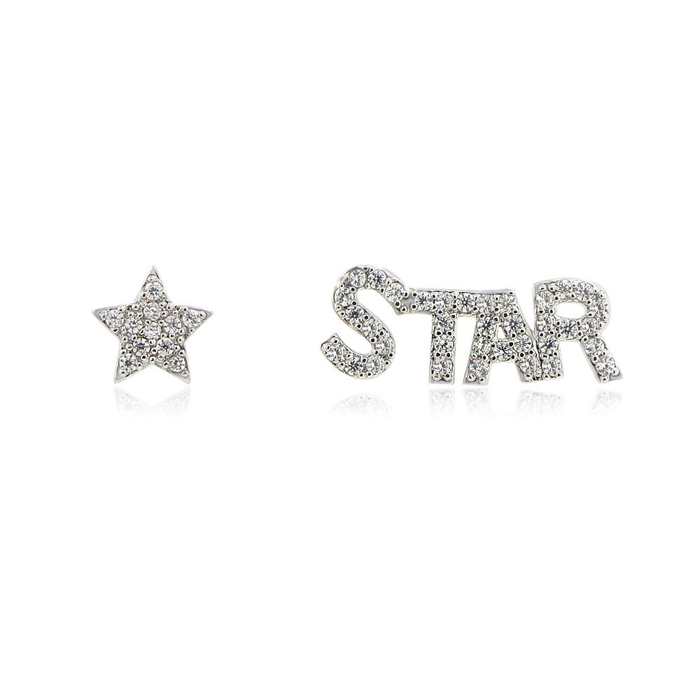 Une paire de boucles d'oreilles asymétriques en solitaire et en script 'Star' avec des pierres en zircon cubique étincelantes, présentées sur une surface blanche propre.
