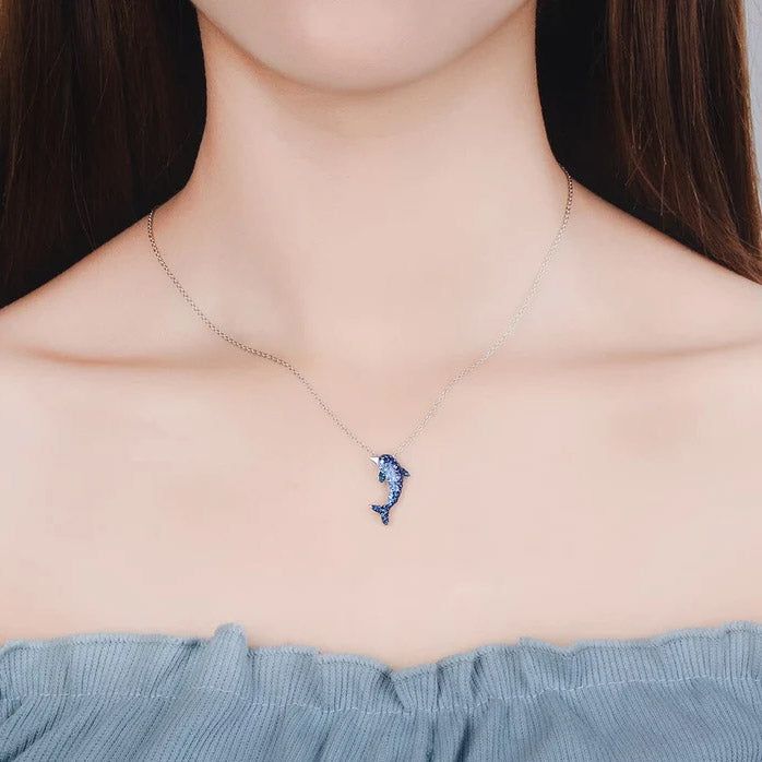 Un primer plano del collar de colgante de delfín de plata esterlina 925, mostrando las intrincadas piedras de circonio azul y claro en una cadena de plata.