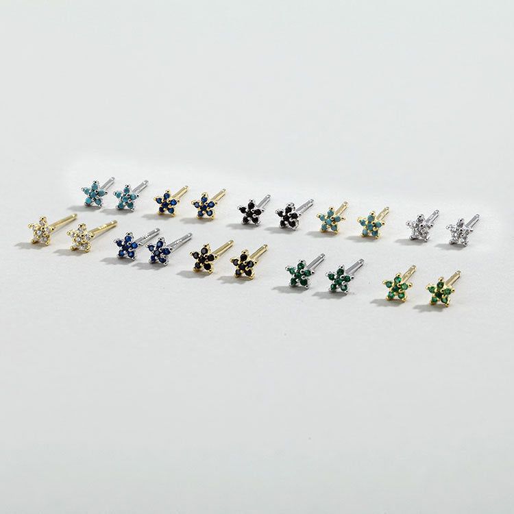 Una collezione vivace di orecchini a perno a forma di fiore in argento sterling 925 con piccole pietre di zirconia colorate, esposte in vari colori di gemme.