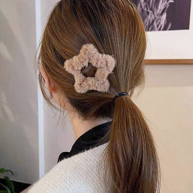 Un modèle présentant la pince à cheveux en peluche douce en forme d'étoile, stylisant une queue de cheval, parfaite pour l'automne et l'hiver.