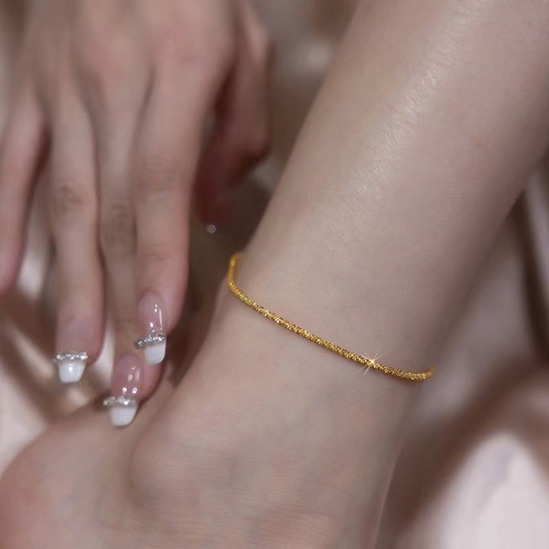 Close-up of a woman's ankle wearing a sparkling gold-tone 925 silver dainty anklet, perfect for special occasions like weddings or parties.