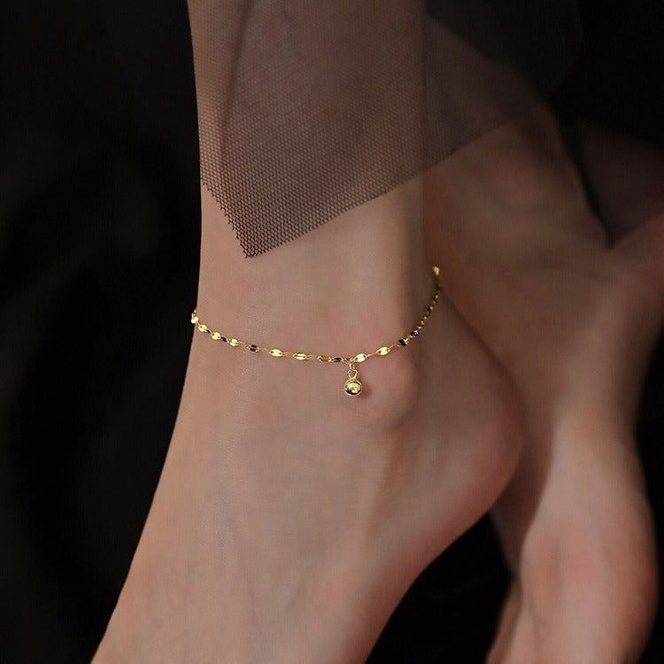 A close-up of a 925 sterling silver anklet in a gold tone, featuring a minimalist cat-shaped charm with a central blue cubic zirconia stone.