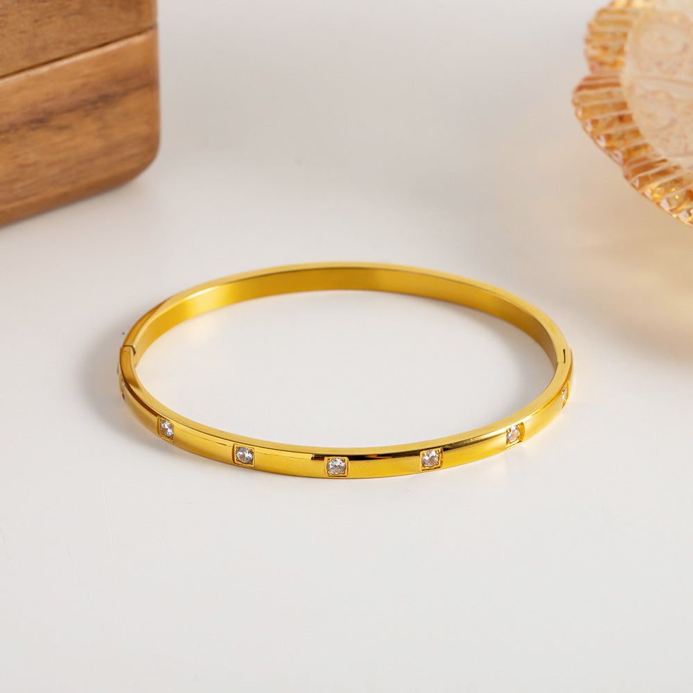 En närbild av ett enda guldpläterat armbandsstålarmband från setet, som framhäver de glittrande vita kubiska zirkonia-stenarna.