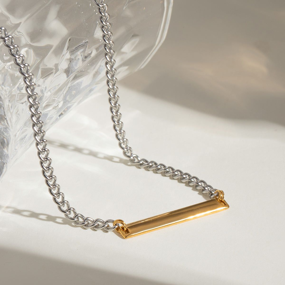 Nahaufnahme der zweifarbigen Balkenanhänger-Halskette aus Edelstahl im Großhandel, die den polierten Goldbalken an einer zarten Silberkette zeigt.