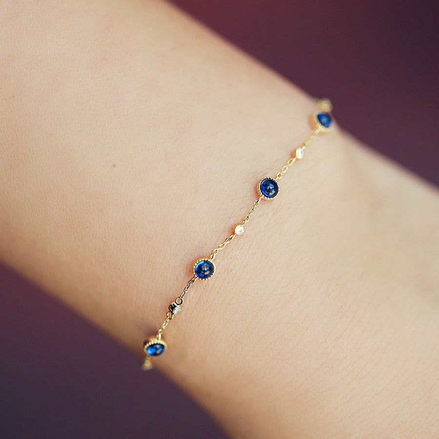 Ein atemberaubendes vergoldetes 925 Sterlingsilberarmband aus einem Großhandelsset, mit funkelnden blauen Zirkon- und klaren Akzentsteinen auf weißem Hintergrund.