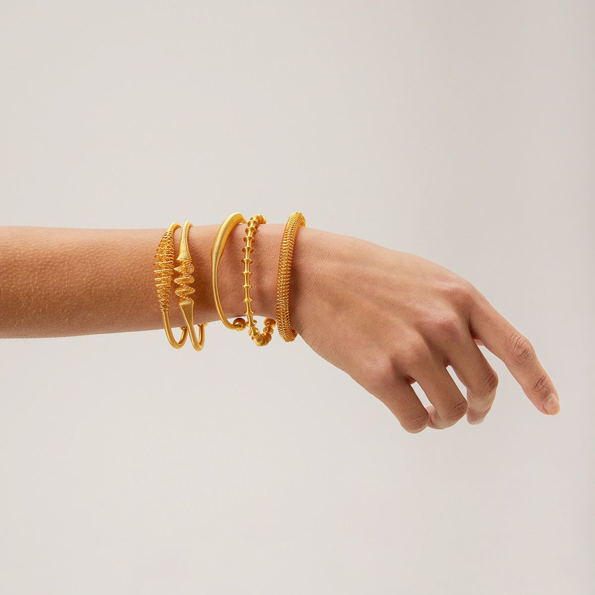 A collection of Nordic vintage style stainless steel open cuff bangles with intricate gold wire wrap designs and varied textures, displayed on a neutral background.