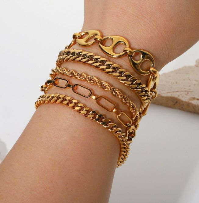 A close-up of a wrist adorned with multiple layers of elegant OEM 18k gold plated bangles, showcasing their polished finish and design.