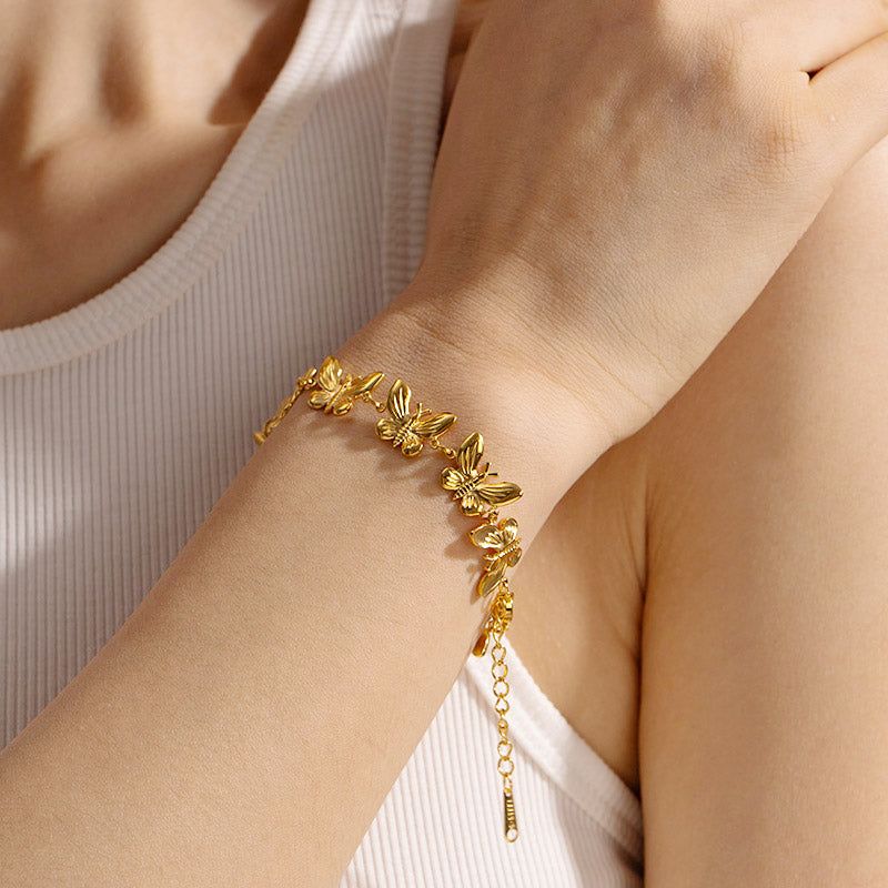 Un primer plano de la pulsera de cadena de mariposa resistente al agua de acero inoxidable del conjunto de cinco, usada en una muñeca.