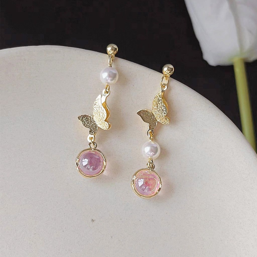 A pair of 14k gold plated butterfly drop earrings with resin pearls and pink gemstones, part of an asymmetrical earring set.