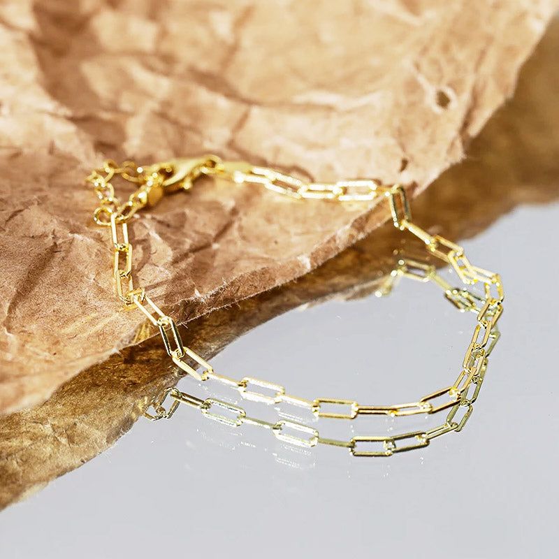 Een close-up productfoto van een 925 sterling zilveren paperclip kettingarmband met een gouden afwerking, weergegeven op een neutrale achtergrond.